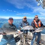 Sportfishers in Port Renfrew celebrate their successful day on the water, proudly displaying the magnificent Chinook salmon they reeled in.