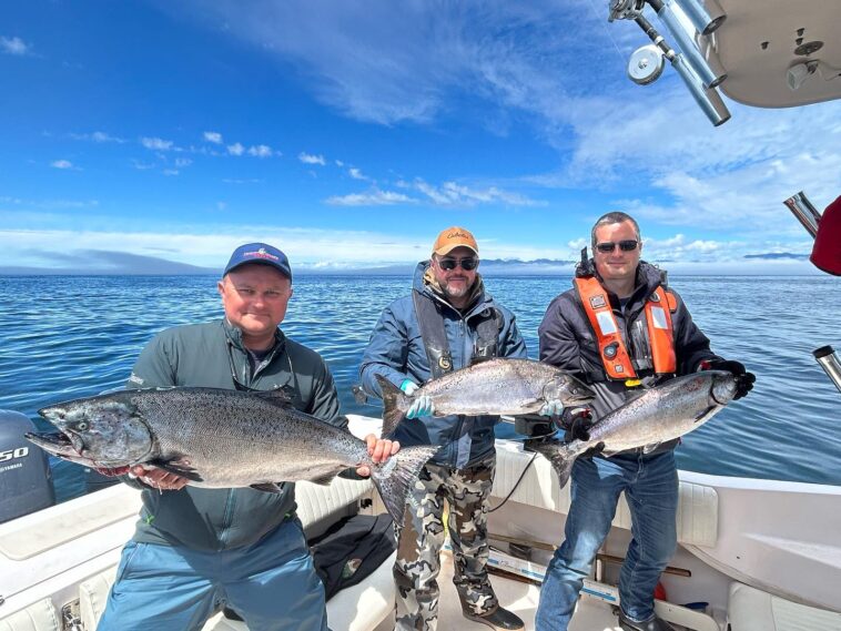 Sportfishers in Port Renfrew celebrate their successful day on the water, proudly displaying the magnificent Chinook salmon they reeled in.