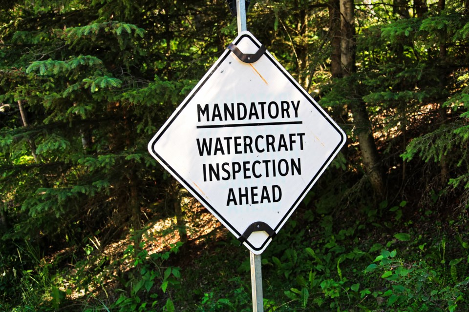 A road sign reading "mandatory watercraft inspection ahead"