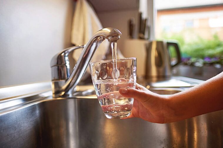 tap water and a person holding a glass under the faucet